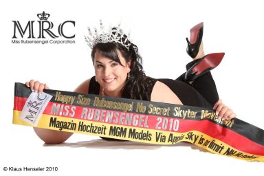 Frau in Abendkleid mit Tiara, hält ein Banner für "Miss Hochschulengel 2019".