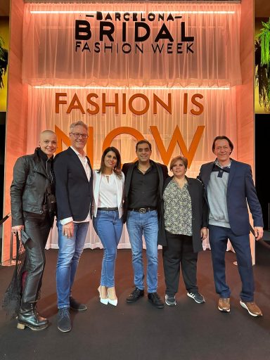 Sechs Personen posieren vor einem Banner der Barcelona Bridal Fashion Week.